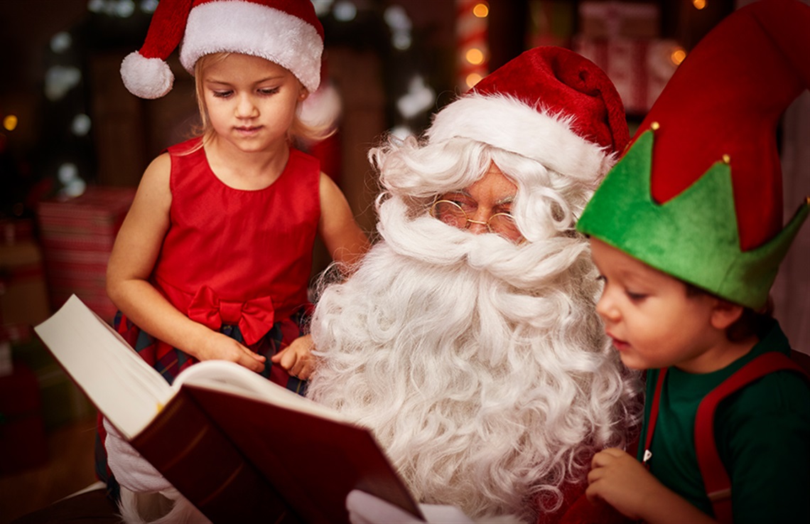 IMage of Santa reading a story to a young boy and girl.