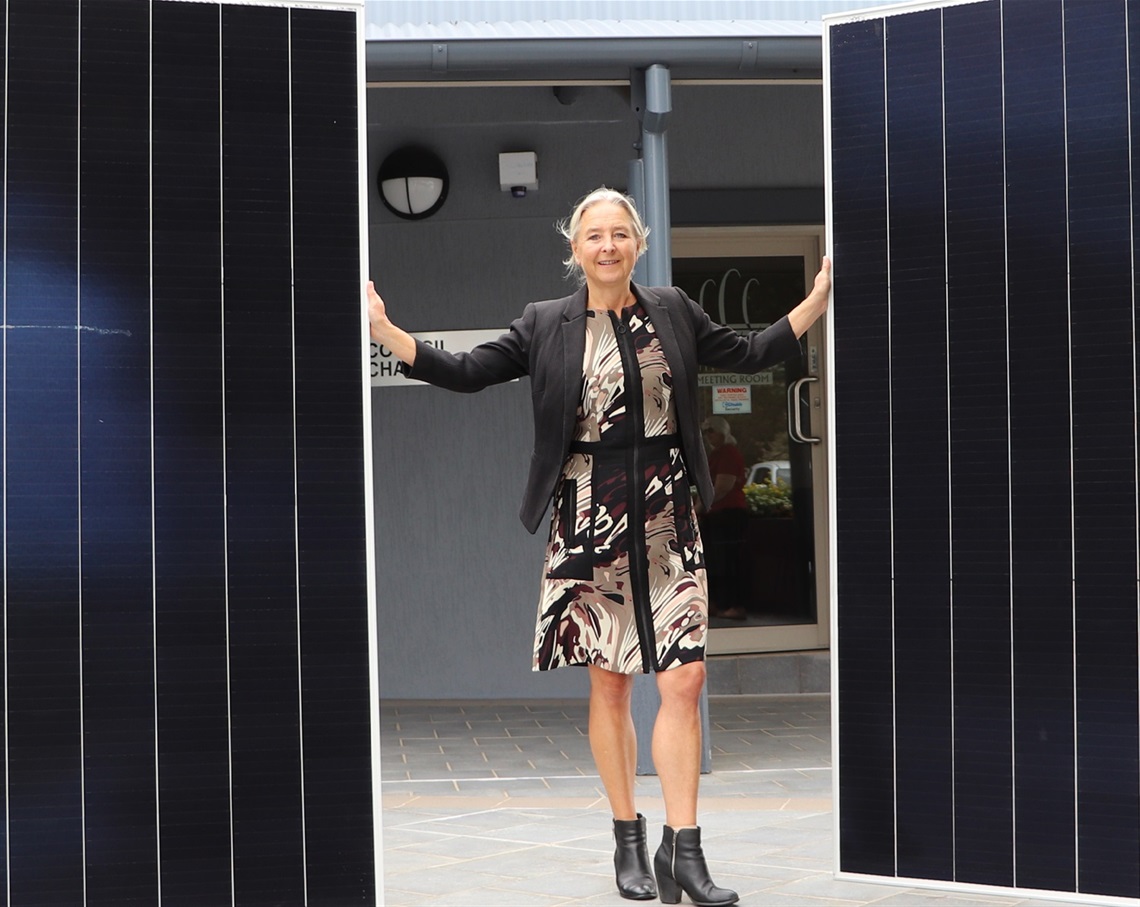 General Manager Lotta Jackson holding solar panels in front of Council's Administration Building.