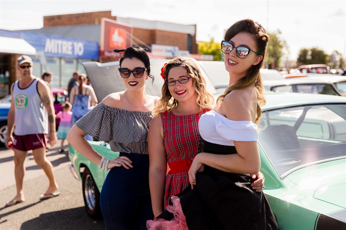 Three women in 50s style dress standing in front of a vintage car at the 2021 Kurri Kurri  Nostaliga Festival