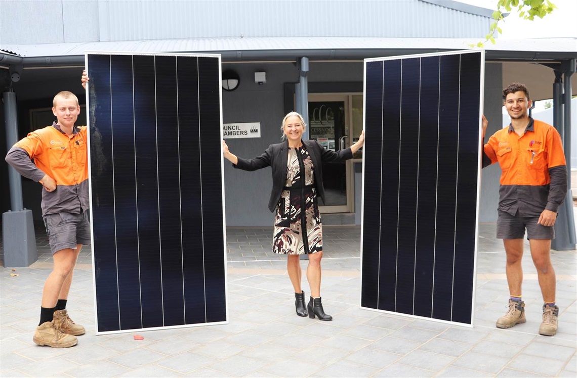 Photo of contractors from Gardel and OTI Power Stefan Vukocic and Gian Redmond holding up solar panels alongside Council's General Manager Lotta Jackson.