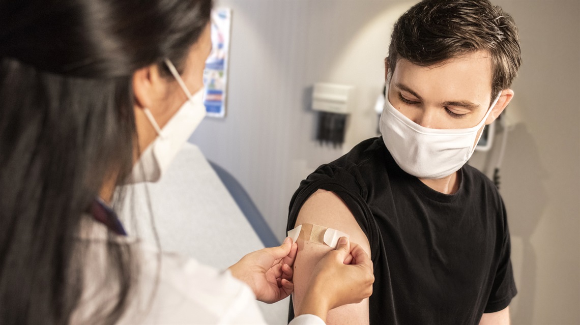 Photo of a female doctor injecting a male patient with the COVID-19 vaccine