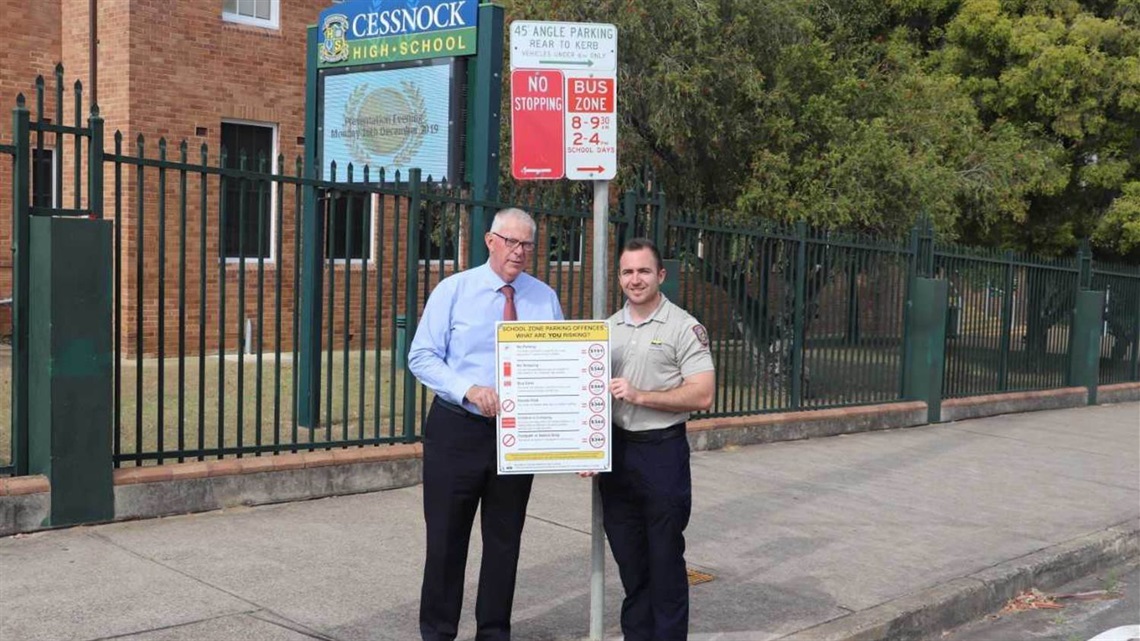 Parking education image with Mayor and Ranger outside a local school